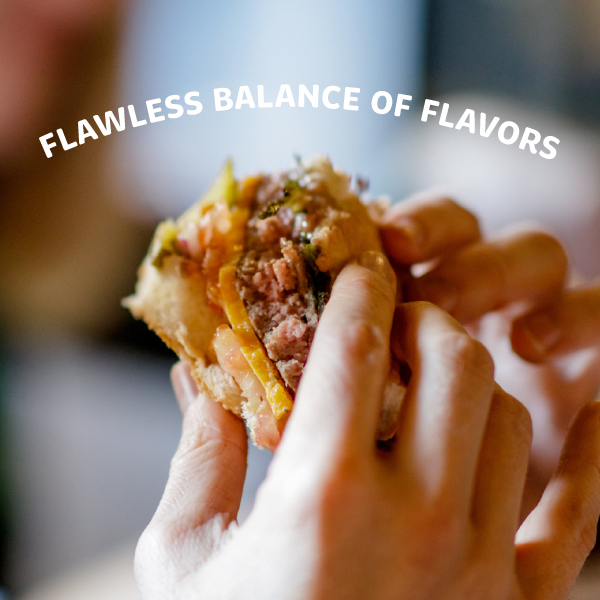 Hands holding a burger with text overlay "Flawless balance of flavors"